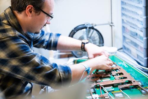 A physics graduate student working on electronics for a research project