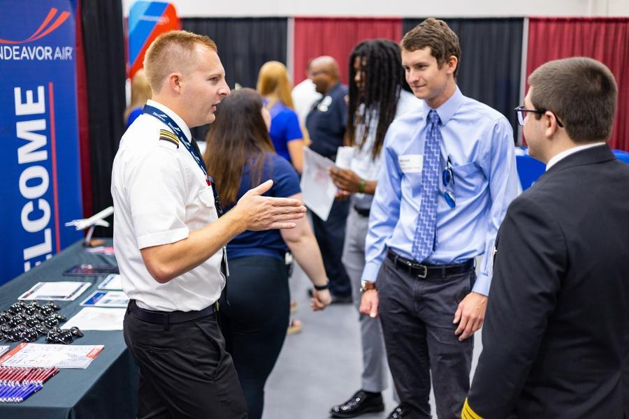 A pilot speaks with students at a career fair