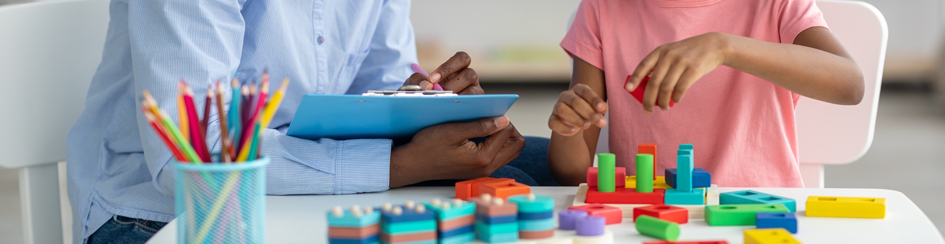 An ABA practitioner works with a child who is stacking blocks