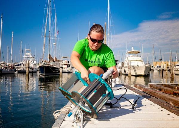 An oceanography student works with a testing device at the marina