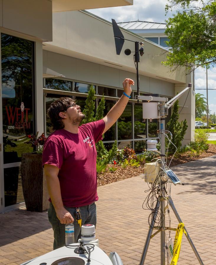 A student works with a weather station on campus.