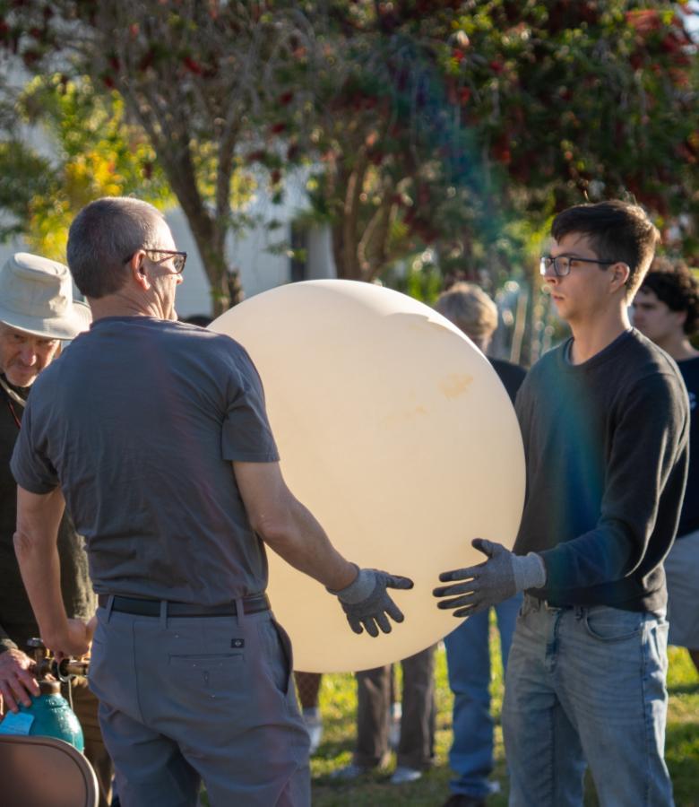 A professor and student preparing to launch a weather balloon on campus.