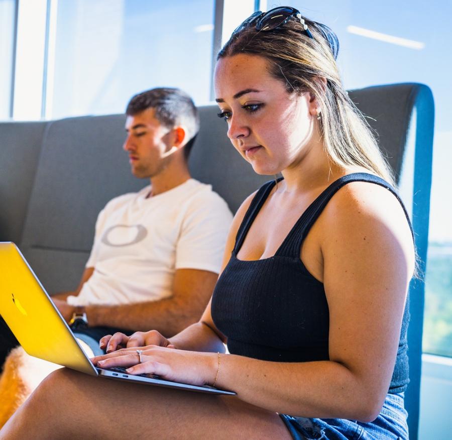 A student looking at her computer in a student area on campus