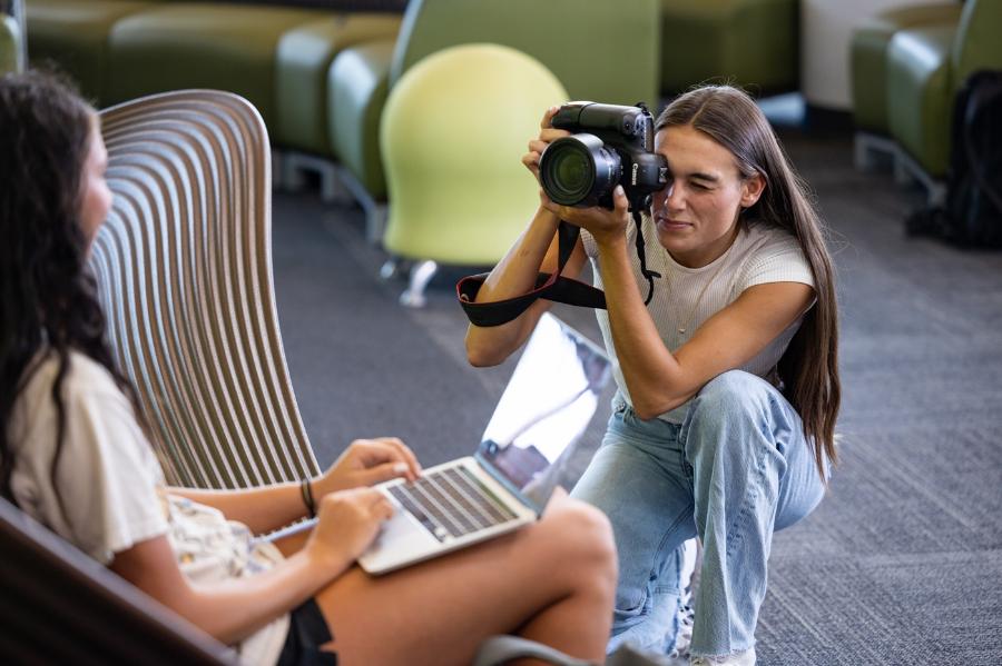 A student taking pictures with a camera for multiplatform journalism.