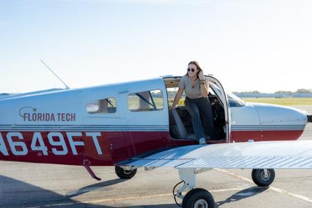 A flight student climbs out of a plane at the airport