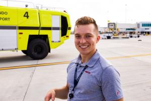 A flight student at Melbourne airport with airport buildings, equipment and fire truck in the background