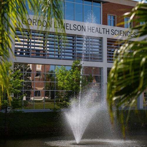 The exterior of Nelson Health Sciences with pond and fountain in the foreground