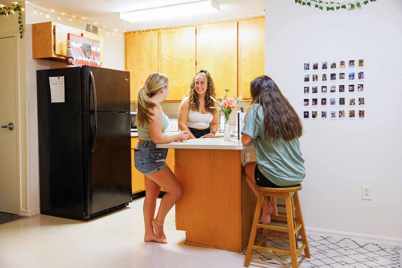 Three students hanging out around the counter in their apartment kitchen area